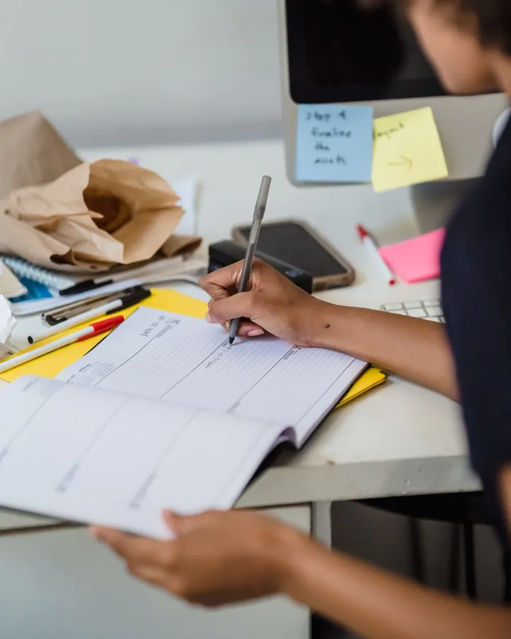 Des mains prennent des notes dans un carnet de planification