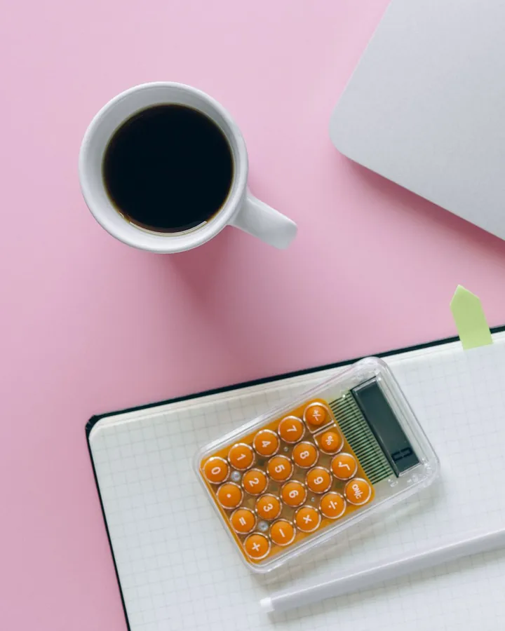 Un bureau avec une calculatrice, un carnet et une tasse de café